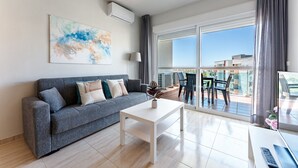 Ein modernes Wohnzimmer mit einem grauen Sofa, einem weißen Couchtisch und einem großen Fenster mit Blick auf Gebäude.