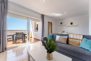 Ein modernes Wohnzimmer mit einer Couch, einem Couchtisch und einem Balkon mit Tisch und Stühlen.
