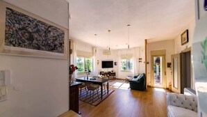 Ein geräumiger Wohnbereich mit Esstisch, Sofa und Kunstwerk an der Wand.