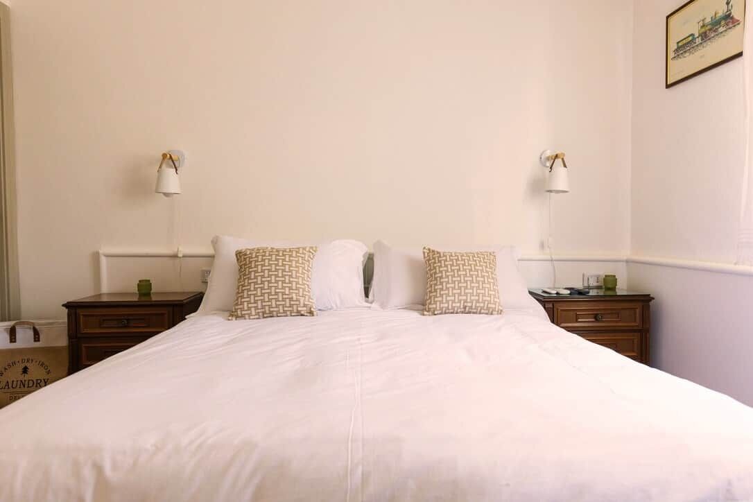 A neatly made bed with patterned pillows, two bedside tables with lamps, and a framed picture on the wall.