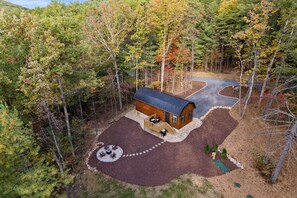 A cabin with a deck, a circular seating area, and a winding driveway surrounded by trees. - Shenandoah, Firepit, peaceful Cabin w/salt water Hot tub! (Luray)