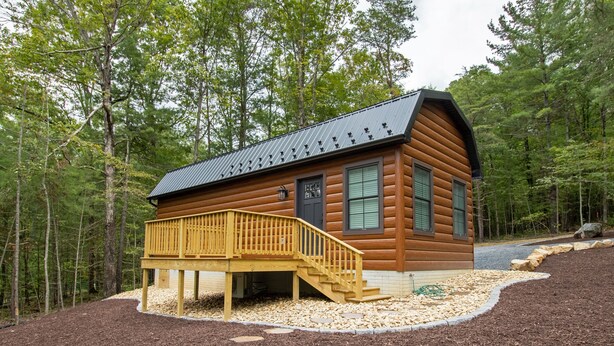 Una baita di legno con una veranda e delle scale che portano all'ingresso.