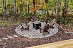 A circular outdoor seating area with Adirondack chairs and a central fire table surrounded by a gravel border. - Shenandoah, Firepit, peaceful Cabin w/salt water Hot tub! (Luray)