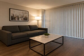 Ein modernes Wohnzimmer mit einer Couch, einem Couchtisch, einer Lampe und einem Stadtbild an der Wand.