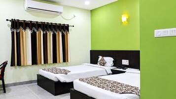 A hotel room with two beds, a ceiling fan, an air conditioning unit, and a green accent wall.