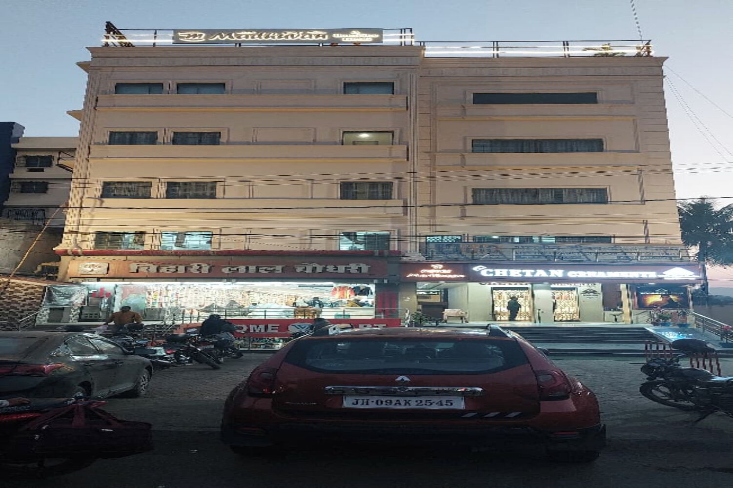 A multi-story building with various shops on the ground floor, including a visible pharmacy and a restaurant.