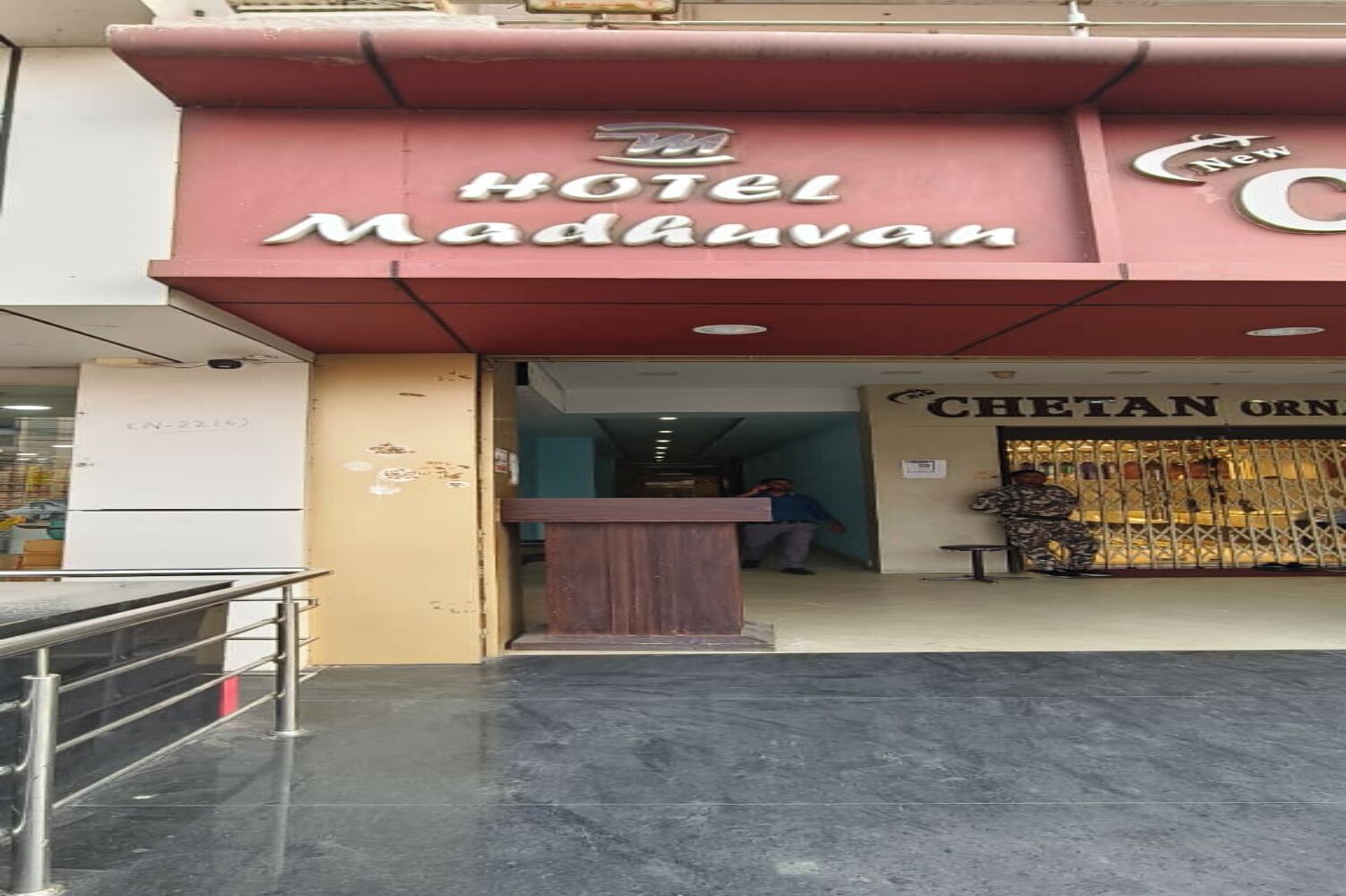 Exterior del Hotel Madavan, con mostrador de recepción y entrada visible.