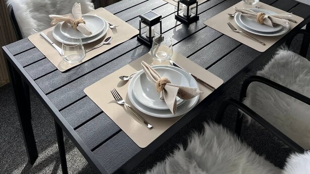A dining table set for four on a balcony with a view of a hillside town. - book2stay: Retro-Alpin Studio with balcony (Laax)