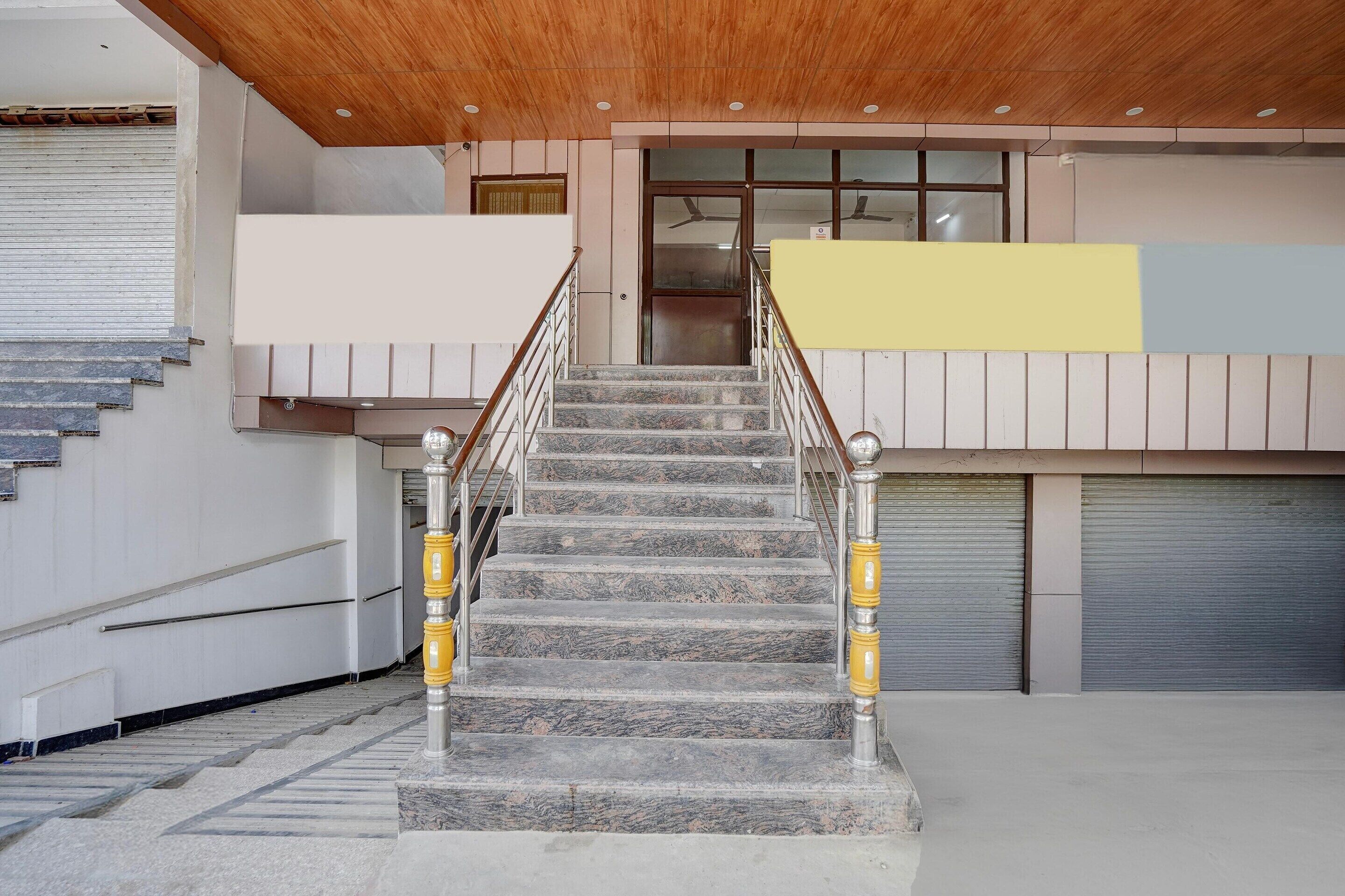 A staircase with marble steps and yellow handrails leading to a building entrance.