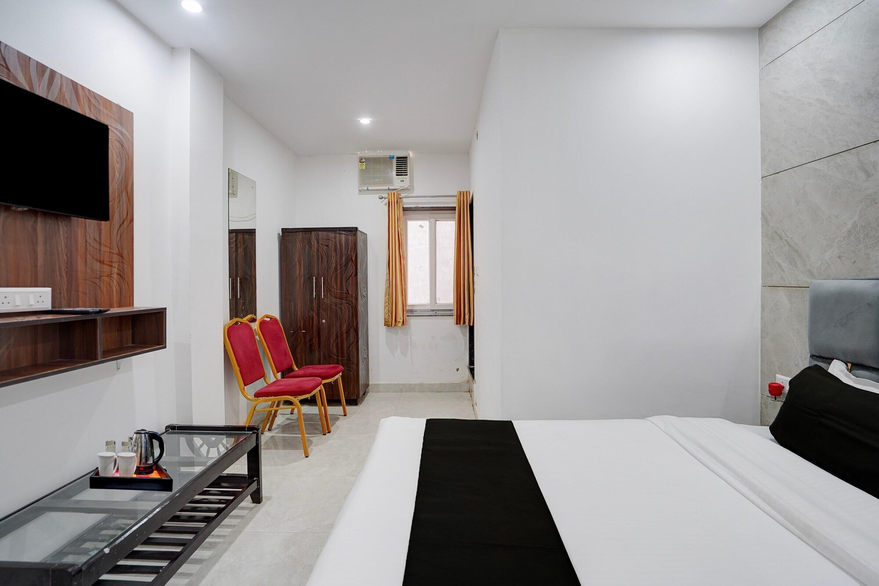 Une chambre d’hôtel comprenant un lit, une télévision, un bureau avec une chaise et une armoire.