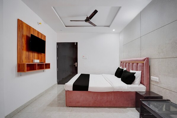 A modern bedroom with a bed, a mounted TV, a ceiling fan, and a door.