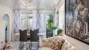 A modern interior with a dining area, a sofa, and a large cityscape painting.