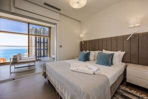 A hotel room with a large bed, a view of the ocean, a balcony with a chair, and a modern design. - Intempo by Holuxe - 074 - 7th floor (Benidorm)