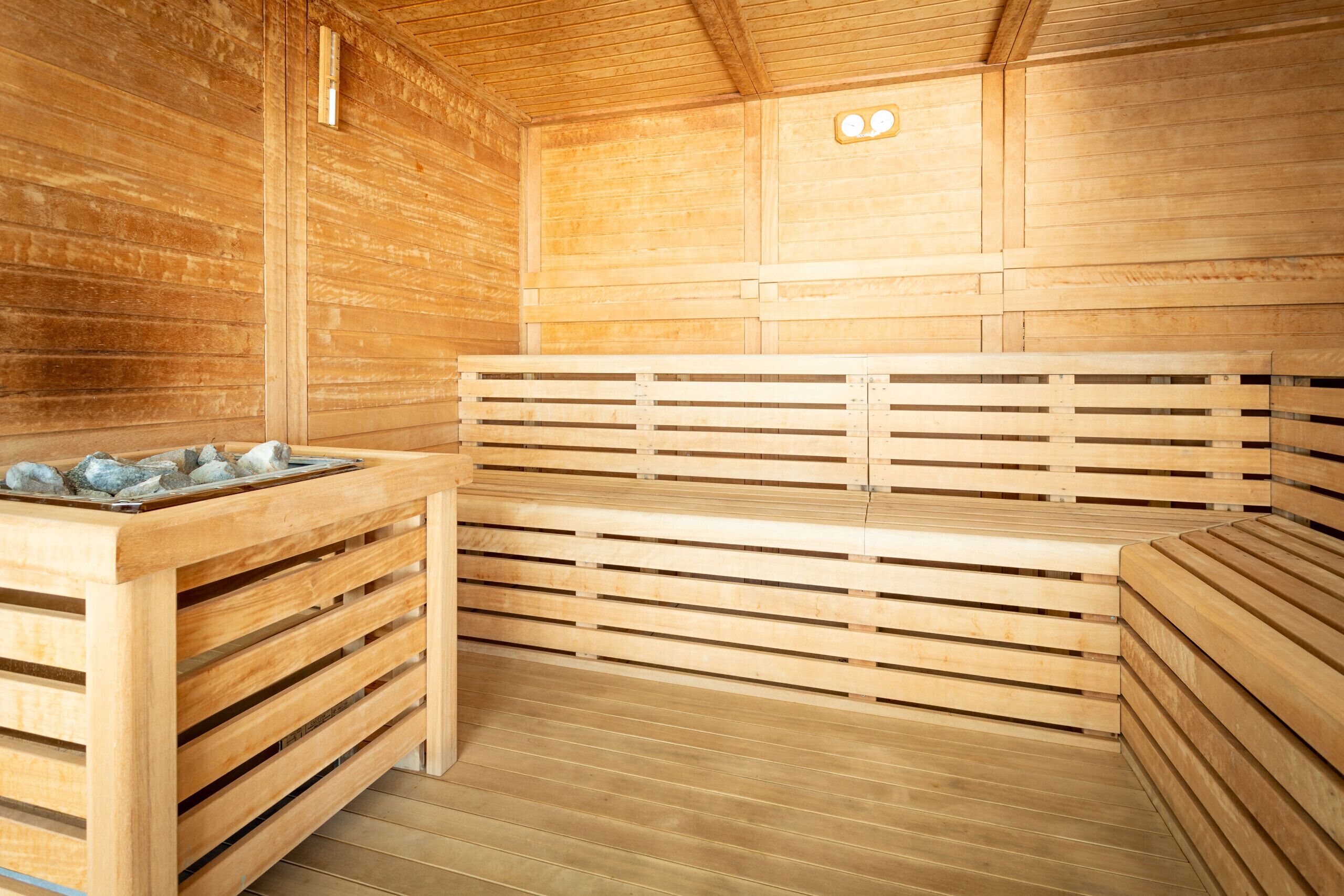 Een sauna met houten banken en een stenen wasbak.