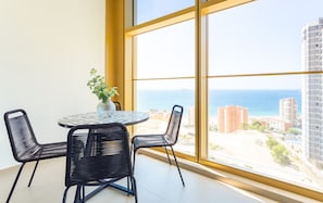 A room with a large window, a round table with chairs, and a vase with flowers. - Intempo by Holuxe - 075 - 7th floor (Benidorm)