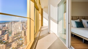 Ein Balkon mit Blick auf die Stadt, ein Bett mit Kissen und eine Schiebetür.