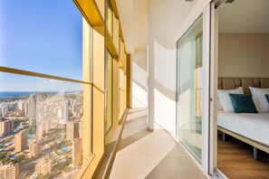 Ein Balkon mit Blick auf die Stadt, ein Bett mit Kissen und eine Schiebetür.
