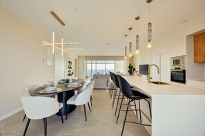 Eine moderne Küche mit Kochinsel, Barhocker und Essbereich mit Aussicht.