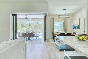 A modern kitchen with a marble countertop, a dining area with a table and chairs, and a large sliding glass door leading to a patio. - SunShine Villa in adorable North Port with pool/spa (North Port)