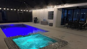 Een zwembad met betegelde rand en een jacuzzi.