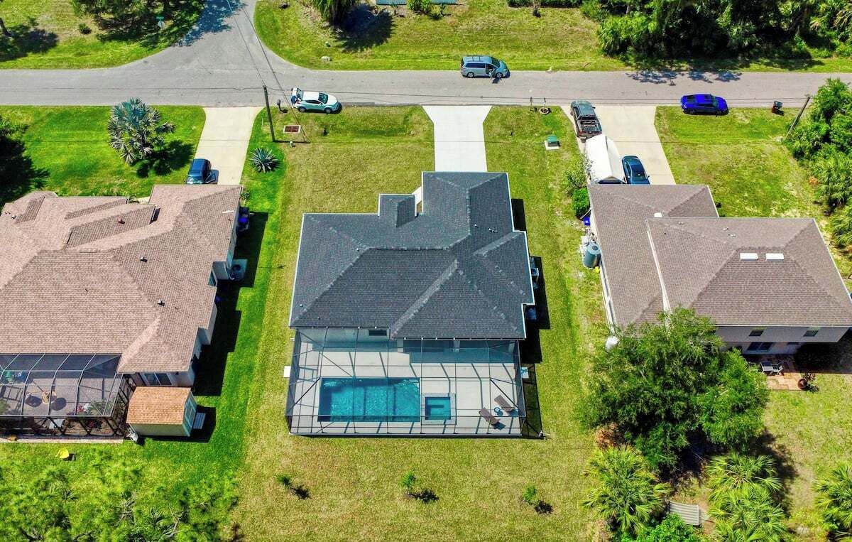 Une maison moderne avec une grande façade vitrée, une piscine et une pelouse bien entretenue.