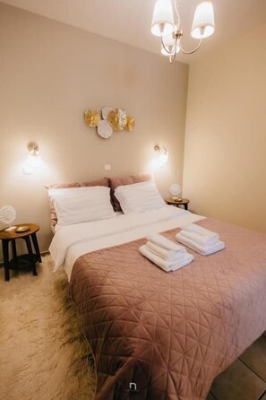 A bedroom with a bed, bedside lamps, decorative wall art, and a fluffy rug. - Kalavrita Milodesi Country House with Fireplace (Kalavrita)