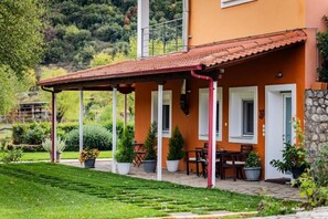 Ein Haus mit überdachter Terrasse, Blumentöpfen und einer Steinmauer.