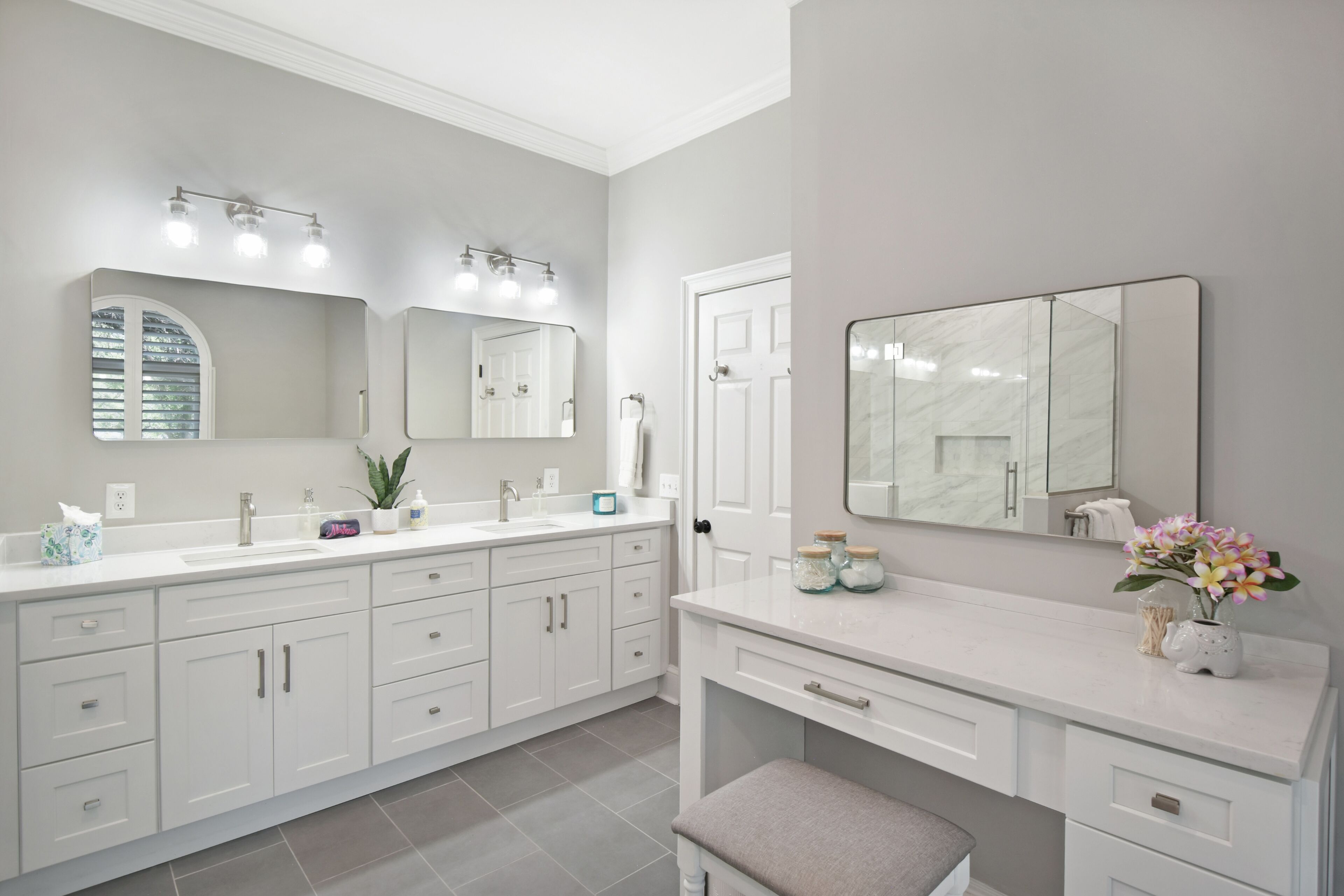 A modern bathroom with a double sink vanity, a large mirror, and a bench.