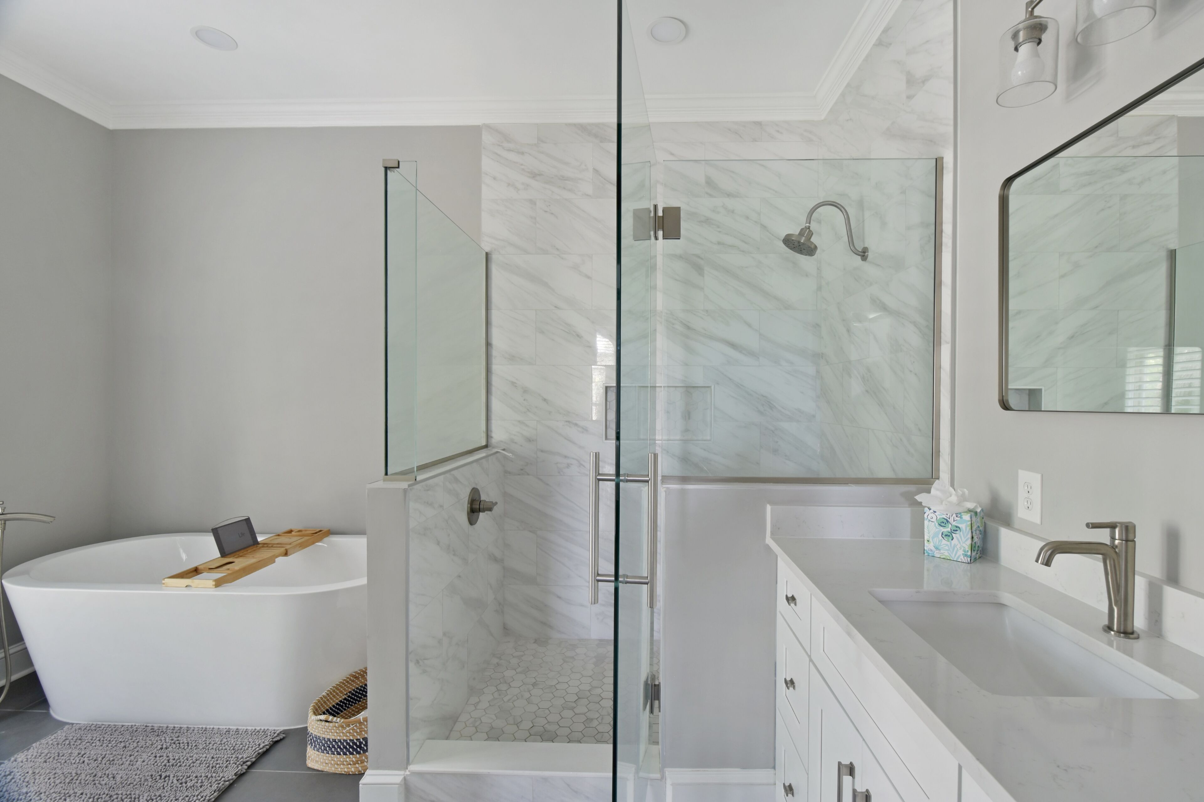 Un baño moderno con ducha de vidrio, una bañera independiente y un tocador con espejo.