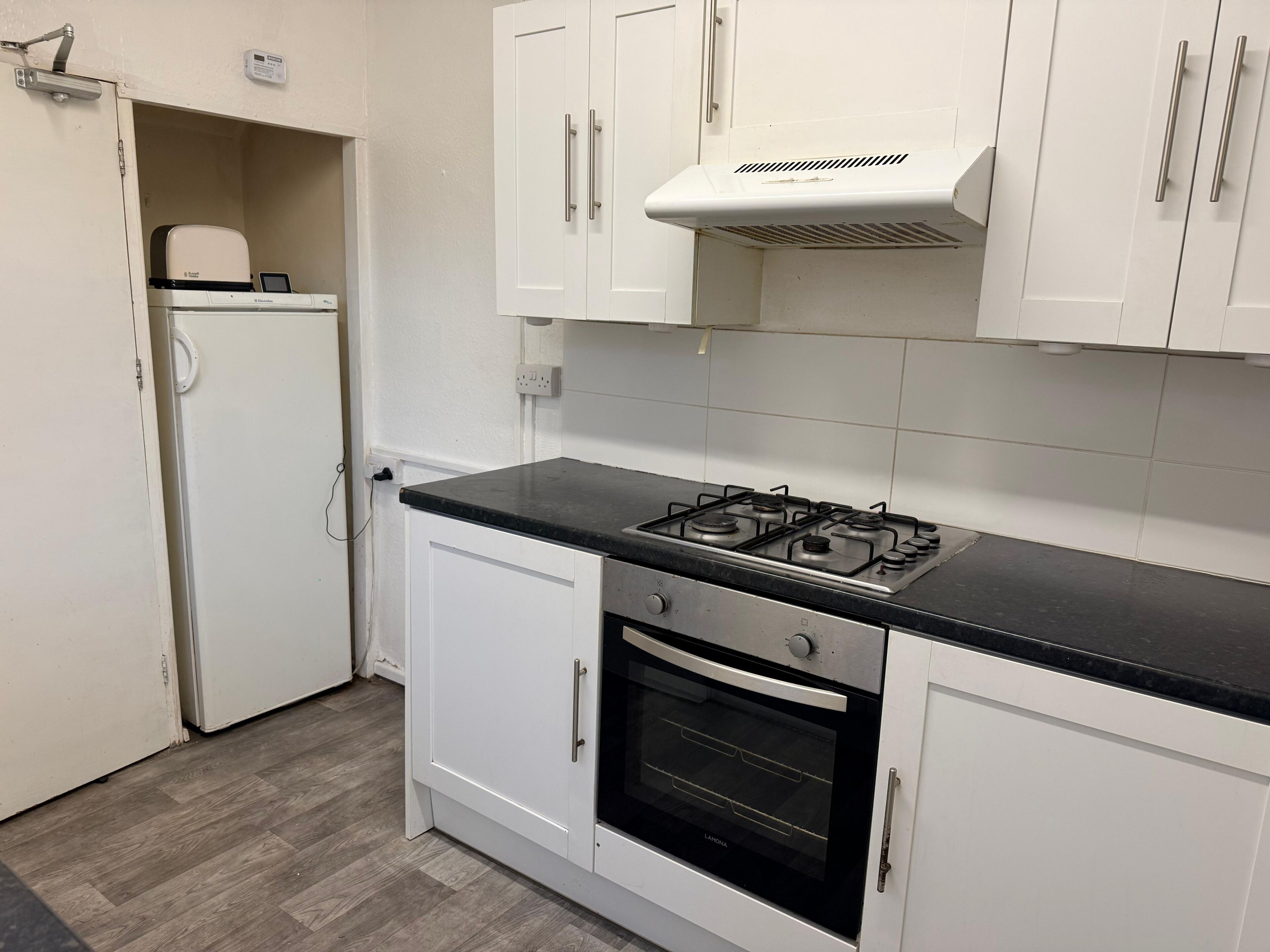 A kitchen with white cabinets, a gas stove, an oven, and a built-in microwave.