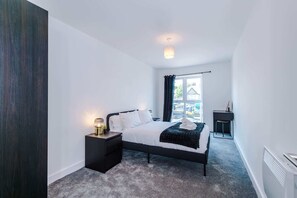 A modern bedroom with a bed, bedside table, and a view of the outside. - Stylish 1BDR Hospitals Nearby (Liverpool)