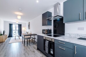 A modern kitchen with a dining area, built-in appliances, and a large window. - Modern and Stylish Flat - 1BDR (Liverpool)