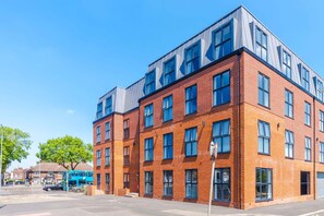 A multi-story brick building with large windows and a flat roof. - Stylish 1BDR Hospitals Nearby (Liverpool)