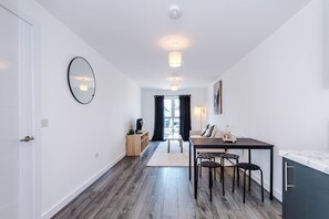 A modern, well-lit room with a dining area, a mirror, and a view through a window. - Modern and Stylish Flat - 1BDR (Liverpool)