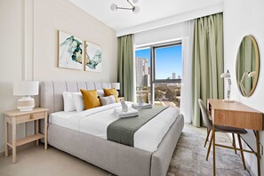 A modern hotel room with a large bed, a desk, a chair, and a view of the city. - Silkhaus Furnished 1BR Stay in Downtown Views II (Dubai)