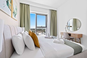 A hotel room with a bed, a desk, a chair, a large window, and a mirror. - Silkhaus Furnished 1BR Stay in Downtown Views II (Dubai)