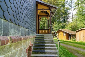 A staircase leading to a wooden building with a tiled roof, surrounded by greenery. - Apartment 'Zur Alten Oberförsterei' with Private Garden (Oberharz am Brocken)