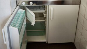 Eine kleine Küche mit Spüle, integriertem Backofen und einem kleinen Kühlschrank.