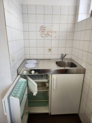 A compact kitchen with a sink, a built-in oven, and a small refrigerator. - "Wiesengrund" Apartment, located on the ground floor of the Werraquelle building, which is ideal for groups (Neuhaus am Rennweg)
