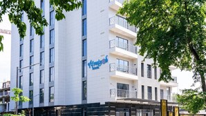 Een modern hotelgebouw met een opvallend bord, meerdere balkons en een overdekte entree.