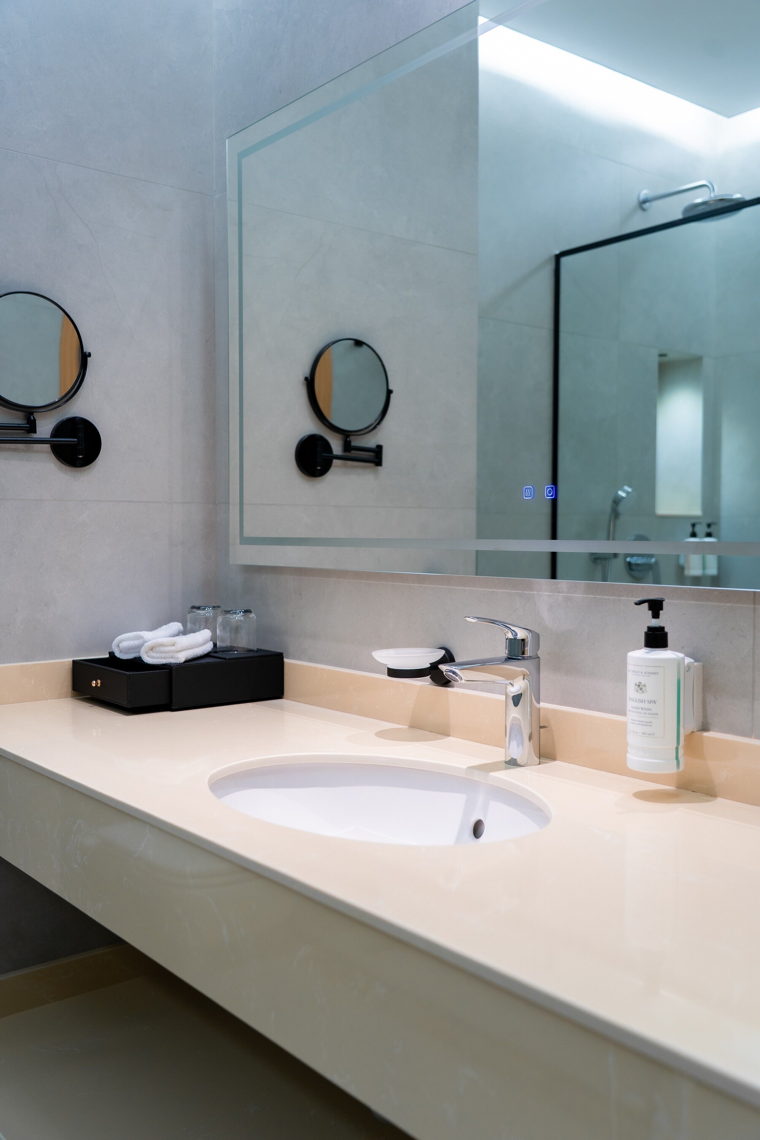 Un baño moderno con un espejo grande, un lavabo y un perchero para toallas.