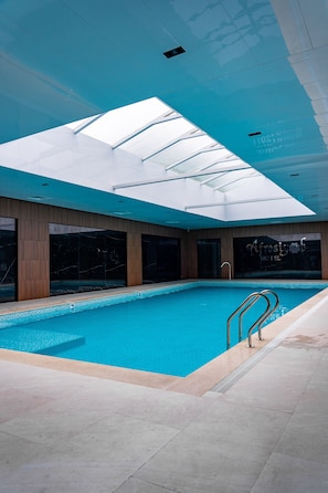 An indoor swimming pool with a skylight, wooden walls, and a sign for 'Afrosyob Hotel'. - Grand Afrosiyob Hotel (Tashkent)