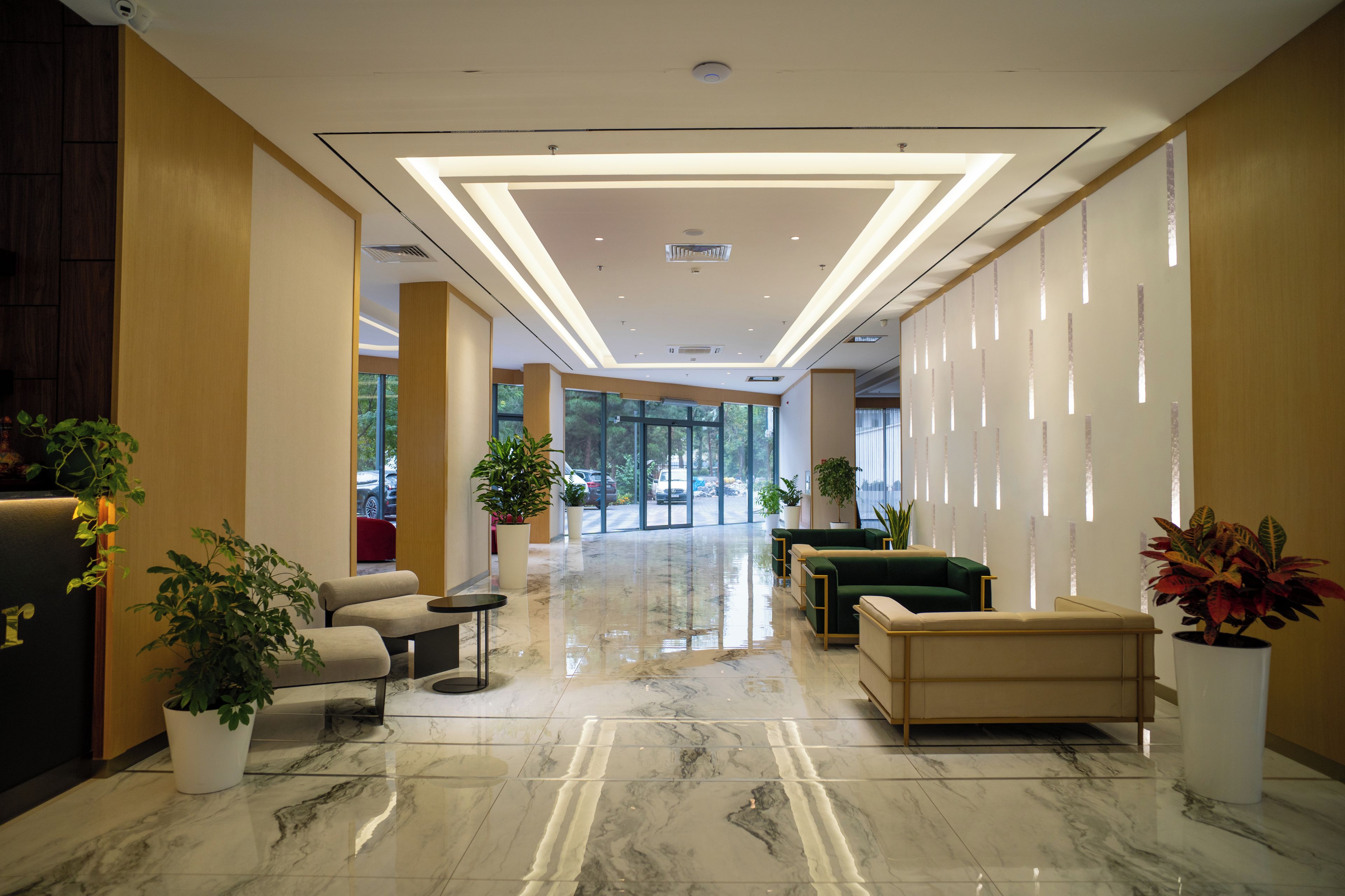 Een hotel lobby met een marmeren vloer, een zithoek en potplanten.