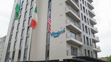 Un hotel de varios pisos, un asta con banderas y un adoquinado a cuadros en la fachada.