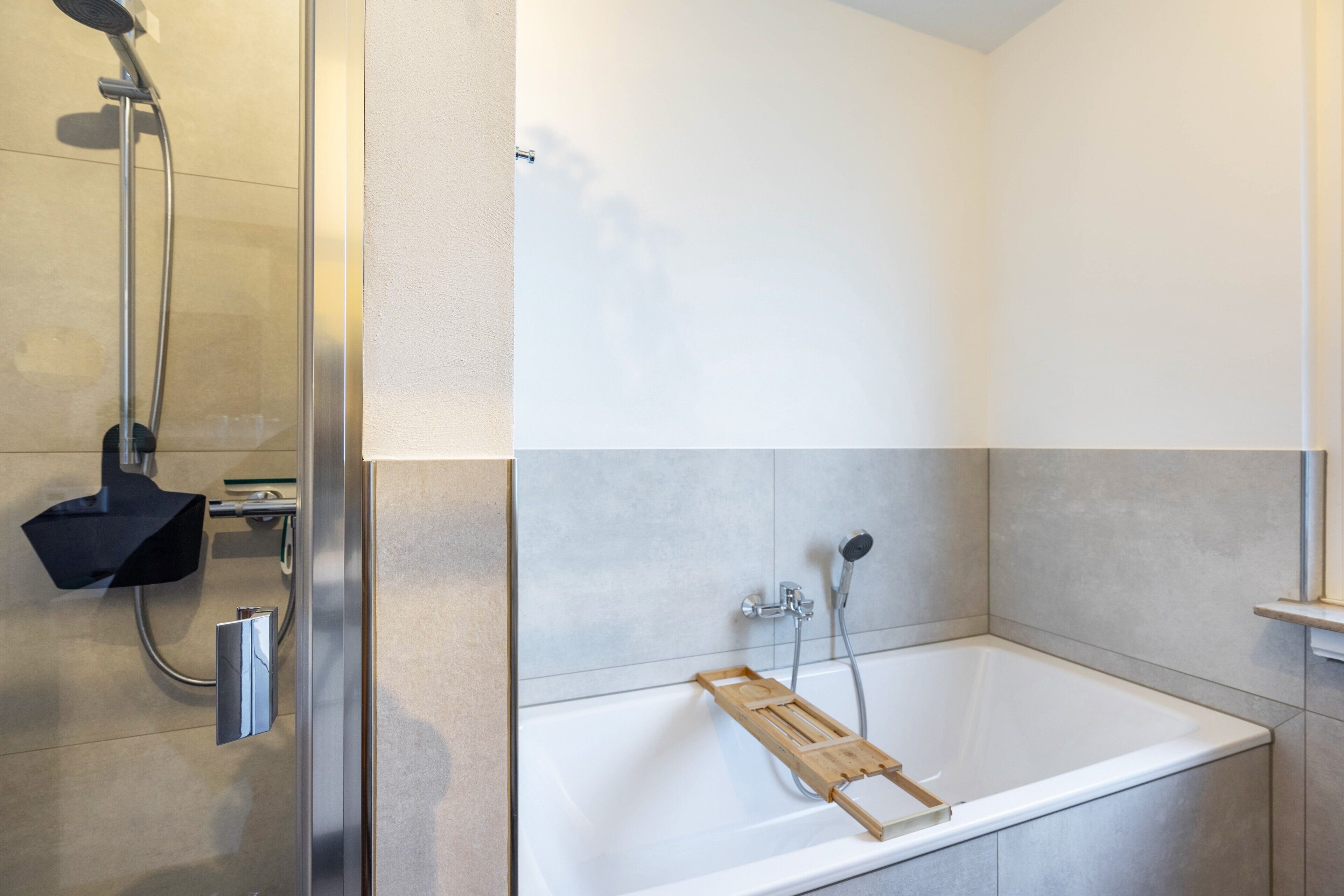 A modern bathroom with a bathtub, shower, and a glass-enclosed shower area.