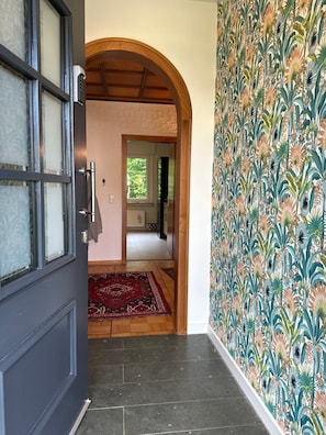 Un couloir avec une porte sombre, une porte en arc de cercle, un mur orné de motifs et un tapis rouge.