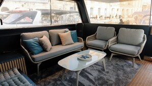 Um interior moderno com um sofá, duas poltronas, uma mesinha e vista para o exterior.