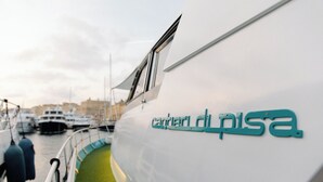 Um barco com o nome 'carterLdi pisa' na lateral, atracado em um porto com outros barcos ao fundo.
