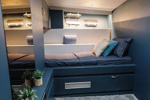 Habitación pequeña y bien iluminada con literas, armarios y una zona de descanso.