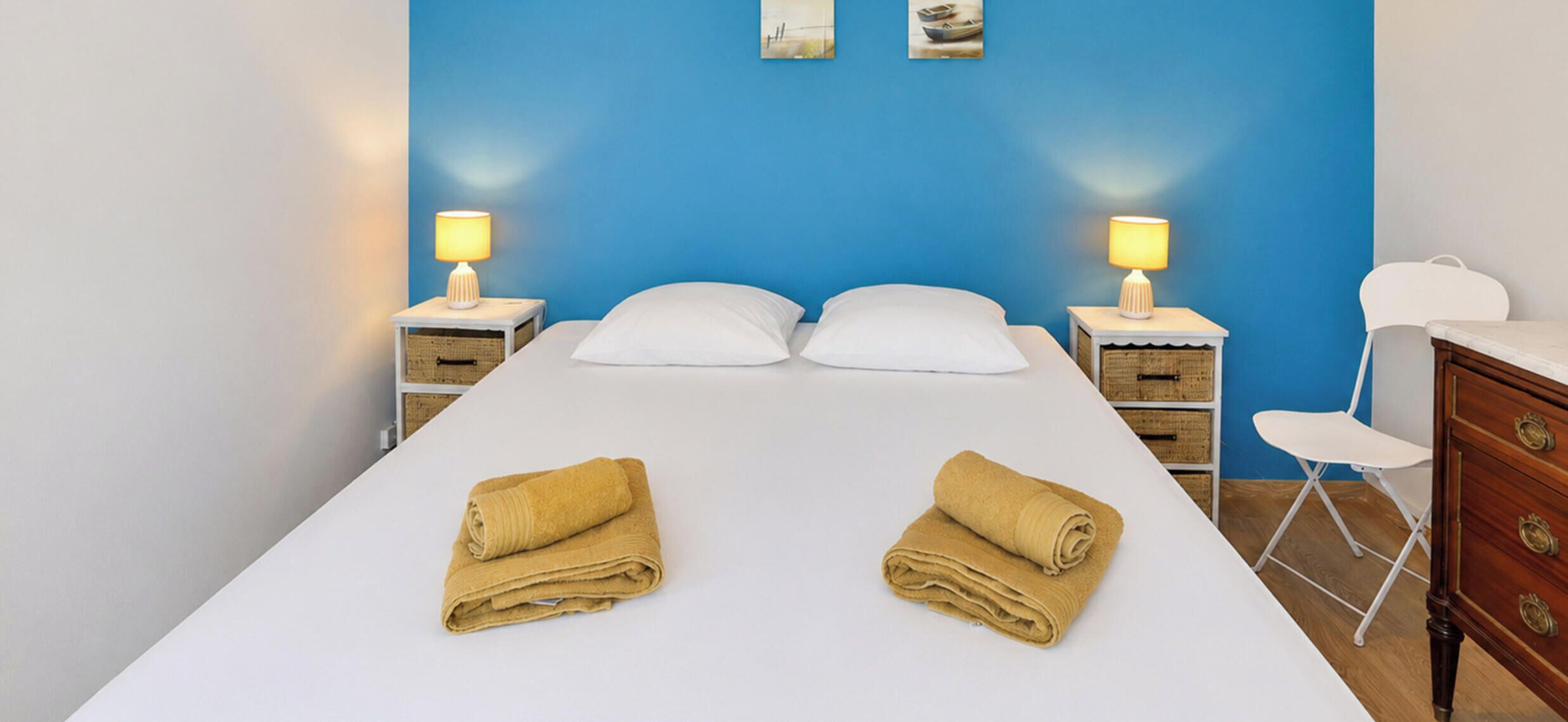 A hotel room with a bed, two nightstands, a chair, and a dresser.